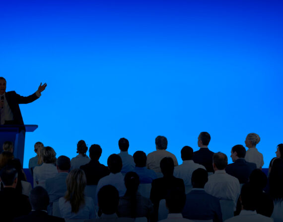corporate-businessman-giving-presentation-large-audience